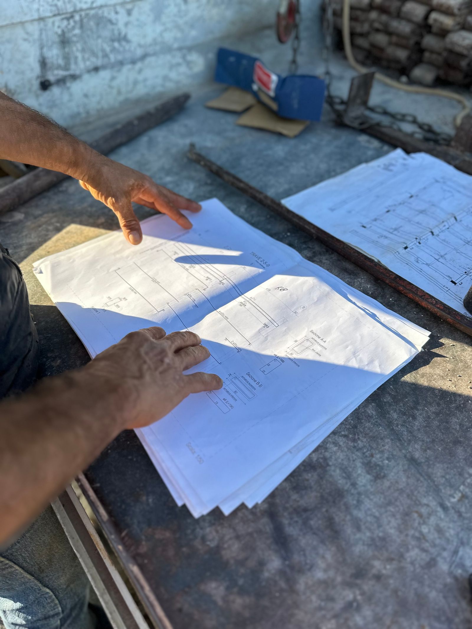 A contractor's hands going over structural drawings on an active job site