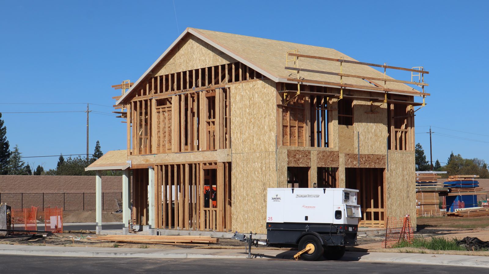 A framed two-story house under construction on a residential street
